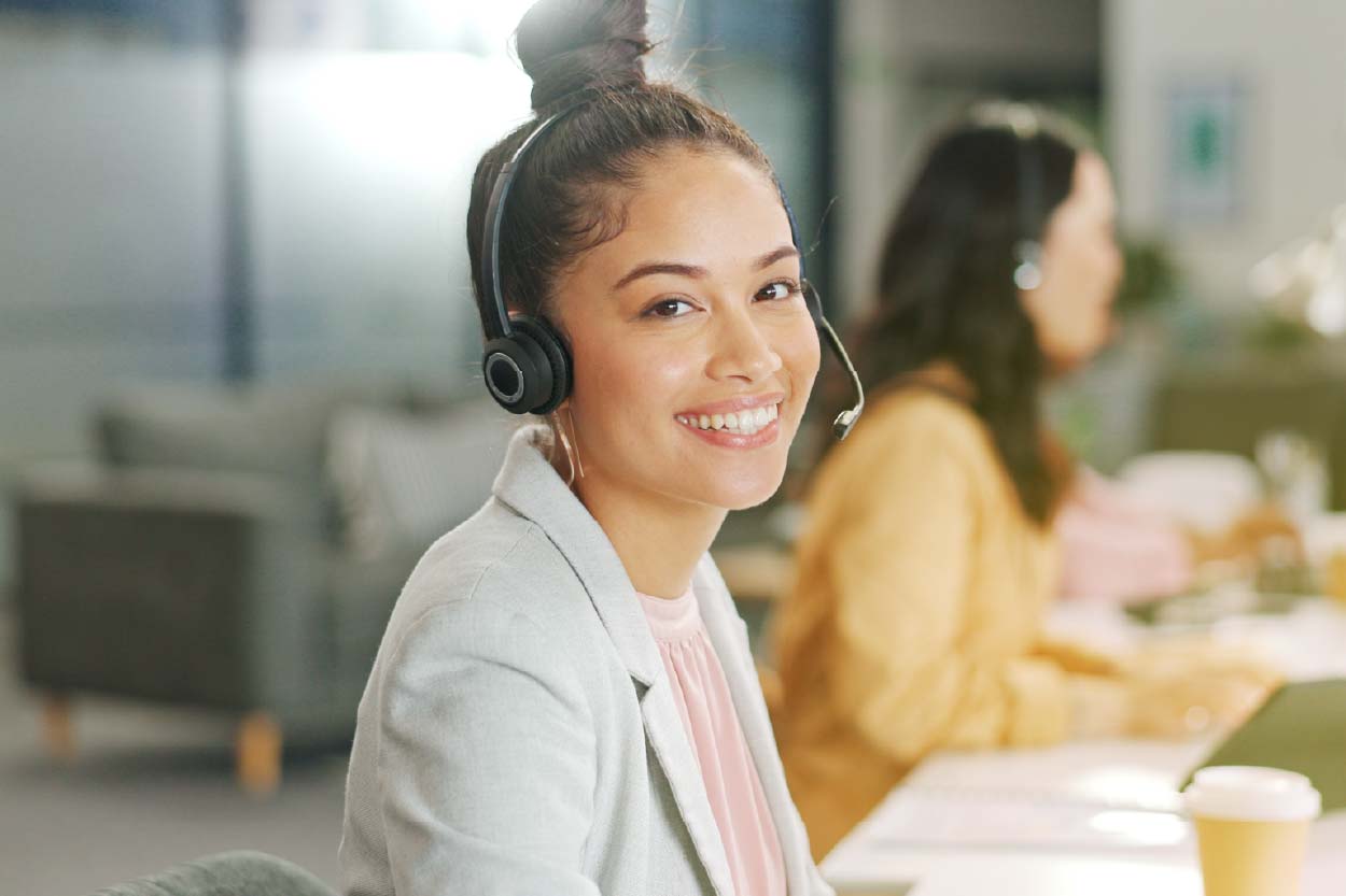 Atendente sorrindo com headset em uma operação de atendimento ao cliente
