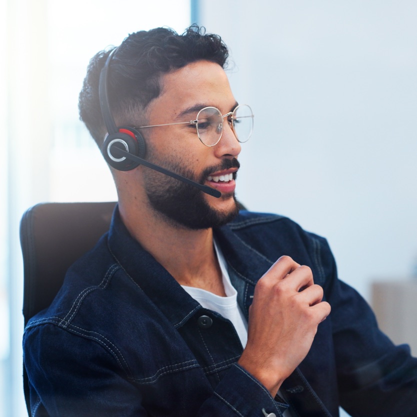 Atendente de headset e óculos sorrindo durante um atendimento
