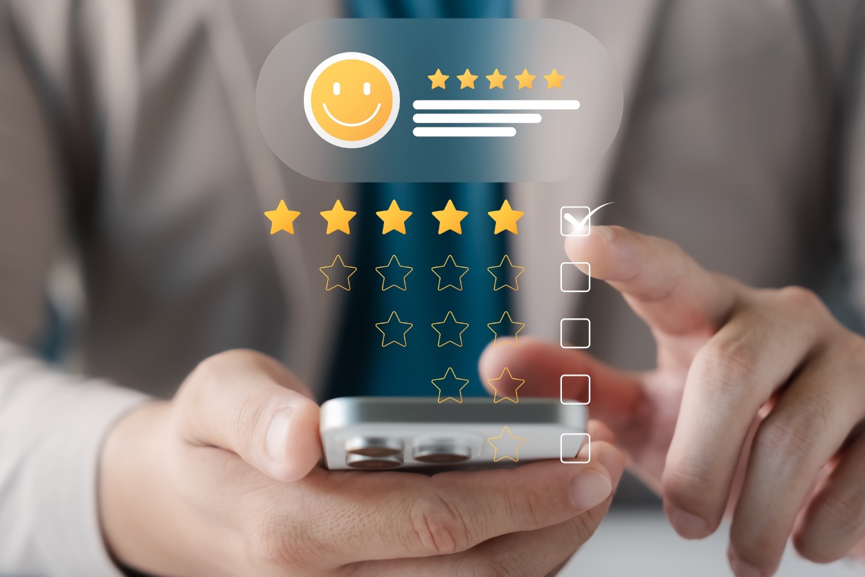 Mão segurando celular com avaliação de cinco estrelas e rosto sorridente em tela flutuante